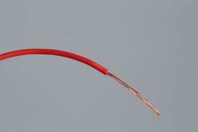 Photo of Red stripped electrical wire on light grey background, closeup