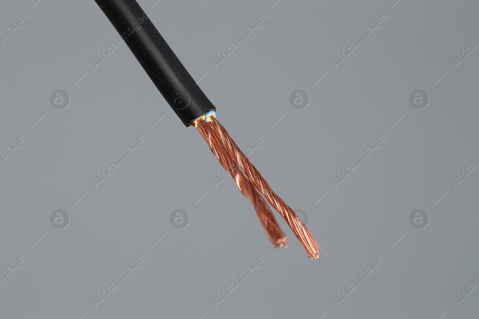 Photo of Black stripped electrical wire on light grey background, closeup