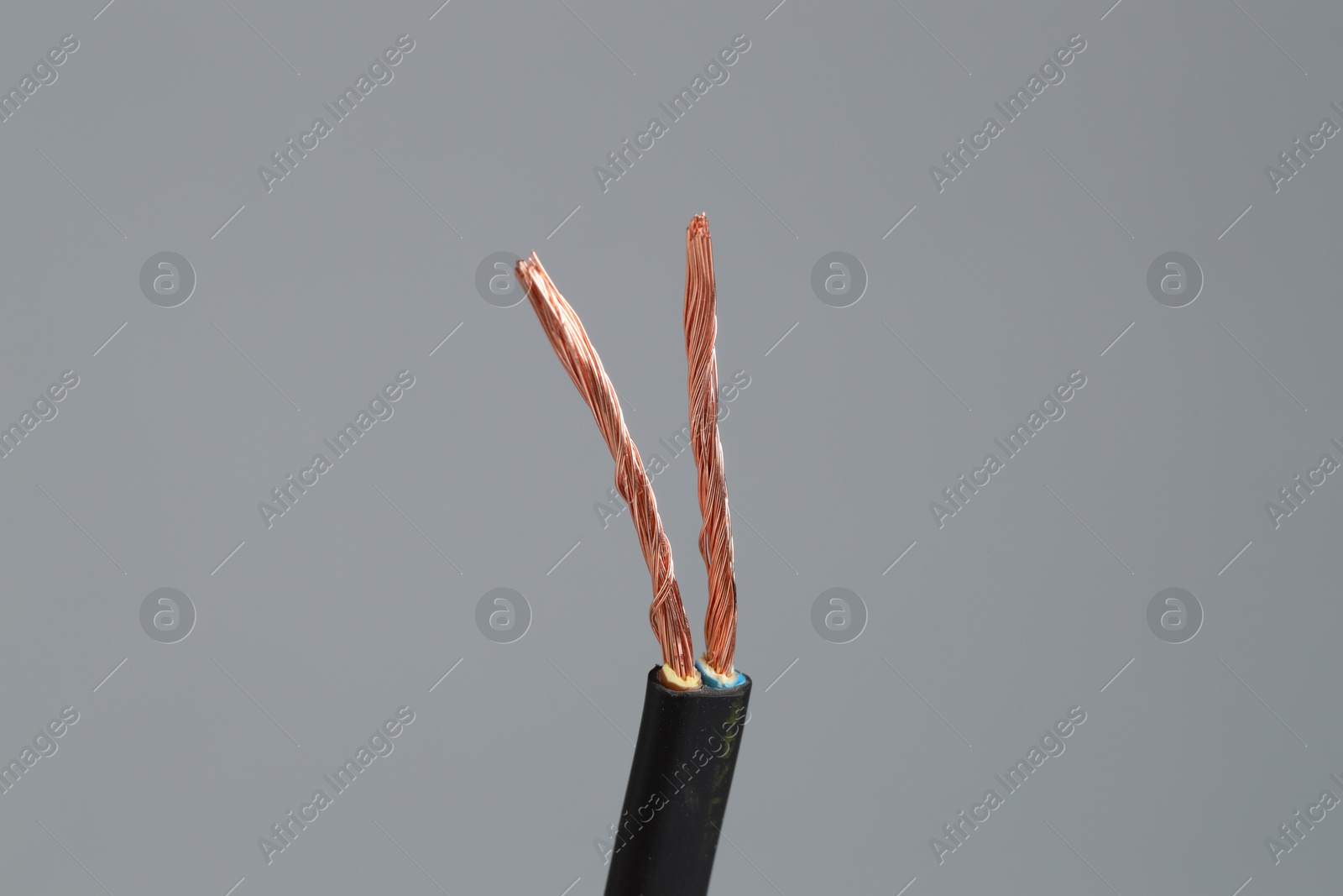 Photo of Black stripped electrical wire on light grey background, closeup