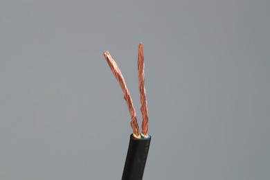 Photo of Black stripped electrical wire on light grey background, closeup