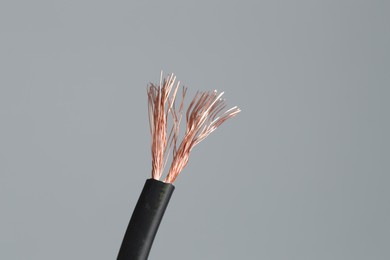 Photo of Black stripped electrical wire on light grey background, closeup