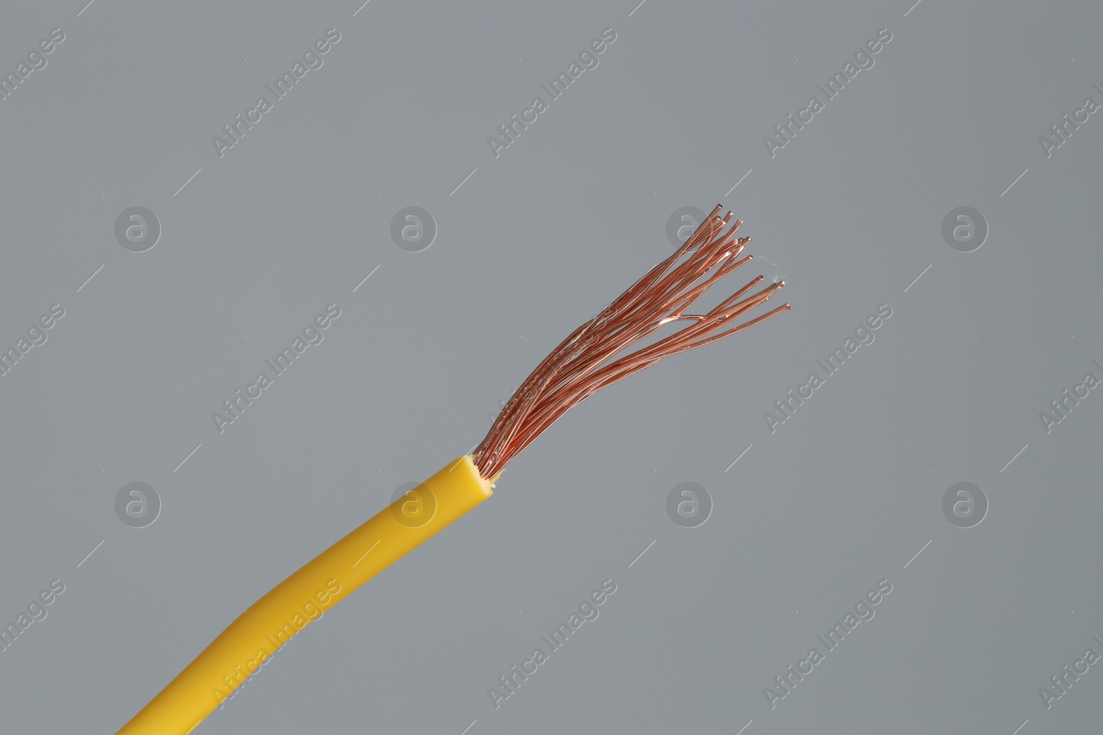 Photo of Yellow stripped electrical wire on light grey background, closeup