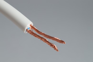 Photo of White stripped electrical wire on light grey background, closeup