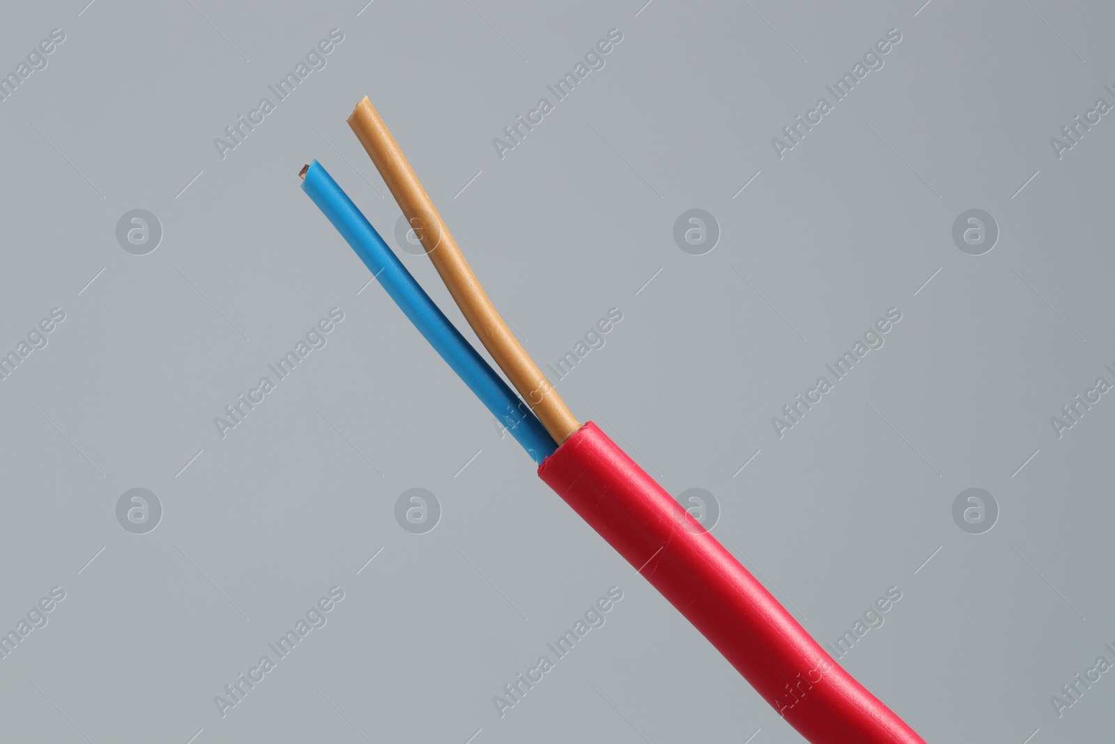 Photo of Red stripped electrical wire on light grey background, closeup