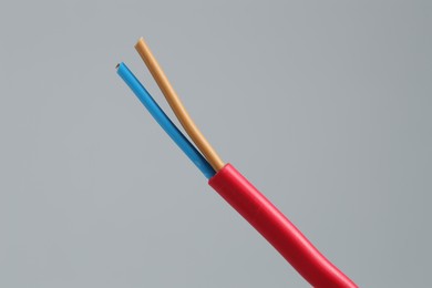 Photo of Red stripped electrical wire on light grey background, closeup