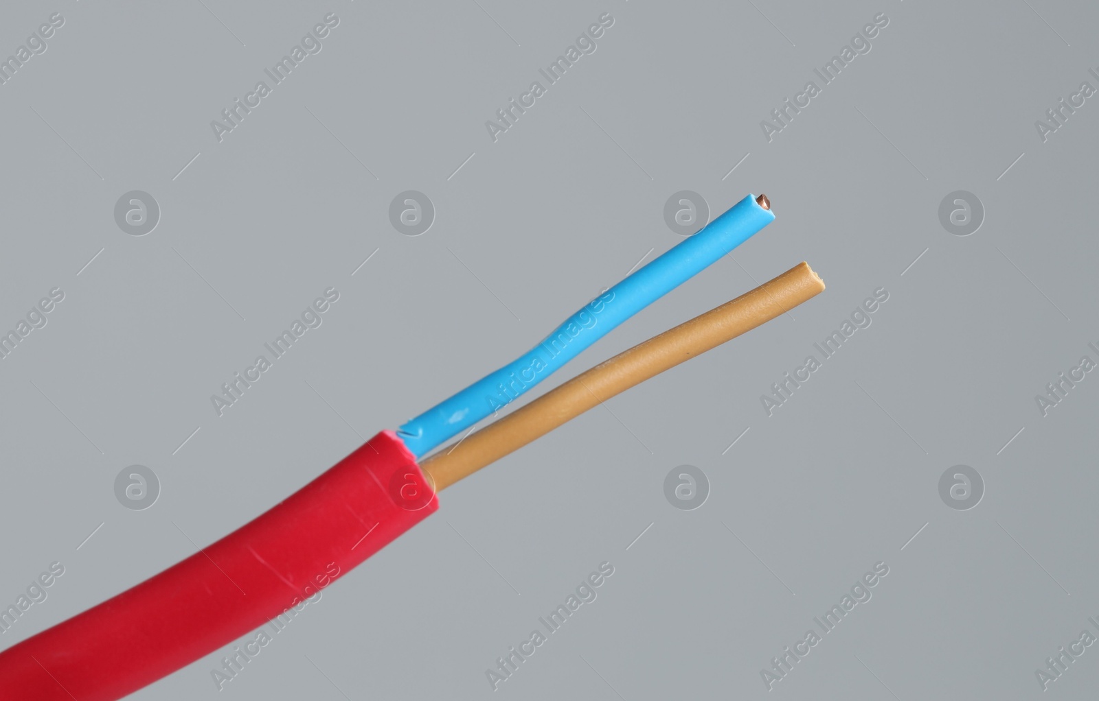 Photo of Red stripped electrical wire on light grey background, closeup