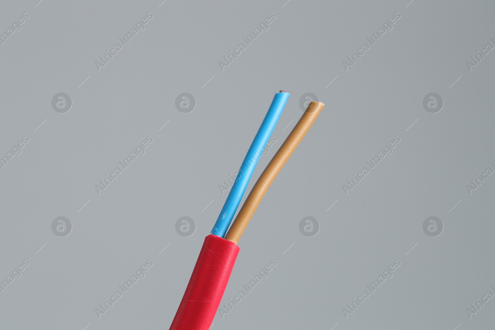 Photo of Red stripped electrical wire on light grey background, closeup