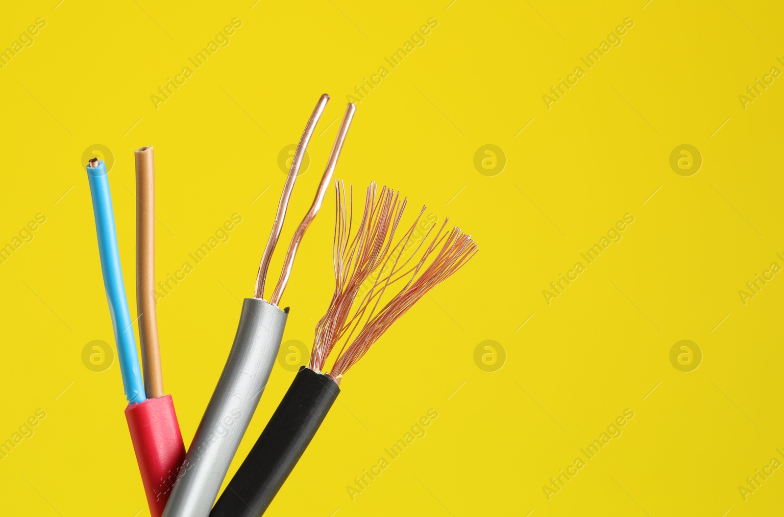 Photo of Many stripped electrical wires on yellow background, closeup