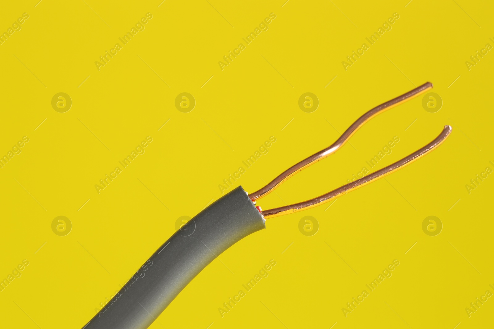 Photo of Grey stripped electrical wire on yellow background, closeup