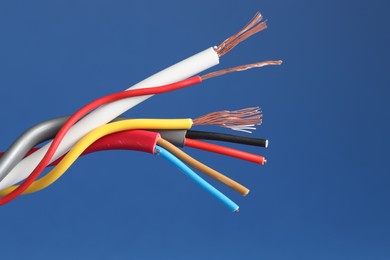 Photo of Many stripped electrical wires on blue background, closeup