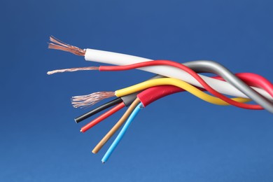 Photo of Many stripped electrical wires on blue background, closeup