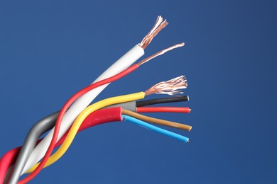 Photo of Many stripped electrical wires on blue background, closeup