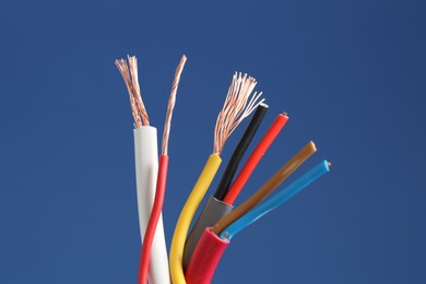 Photo of Many stripped electrical wires on blue background, closeup