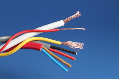 Photo of Many stripped electrical wires on blue background, closeup