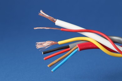 Photo of Many stripped electrical wires on blue background, closeup