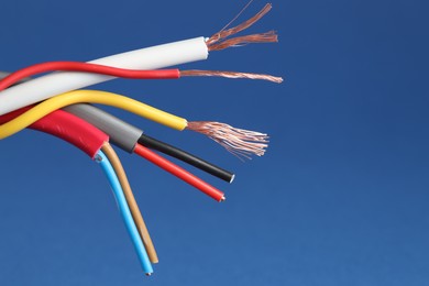 Photo of Many stripped electrical wires on blue background, closeup