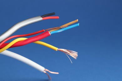 Photo of Many stripped electrical wires on blue background, closeup