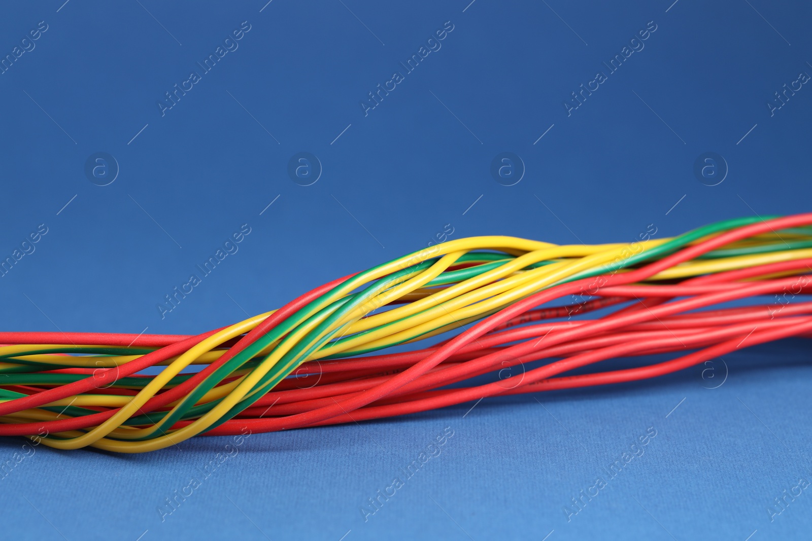 Photo of Many electrical wires on blue background, closeup