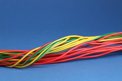 Photo of Many electrical wires on blue background, closeup