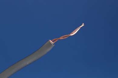 Photo of Grey stripped electrical wire on blue background, closeup