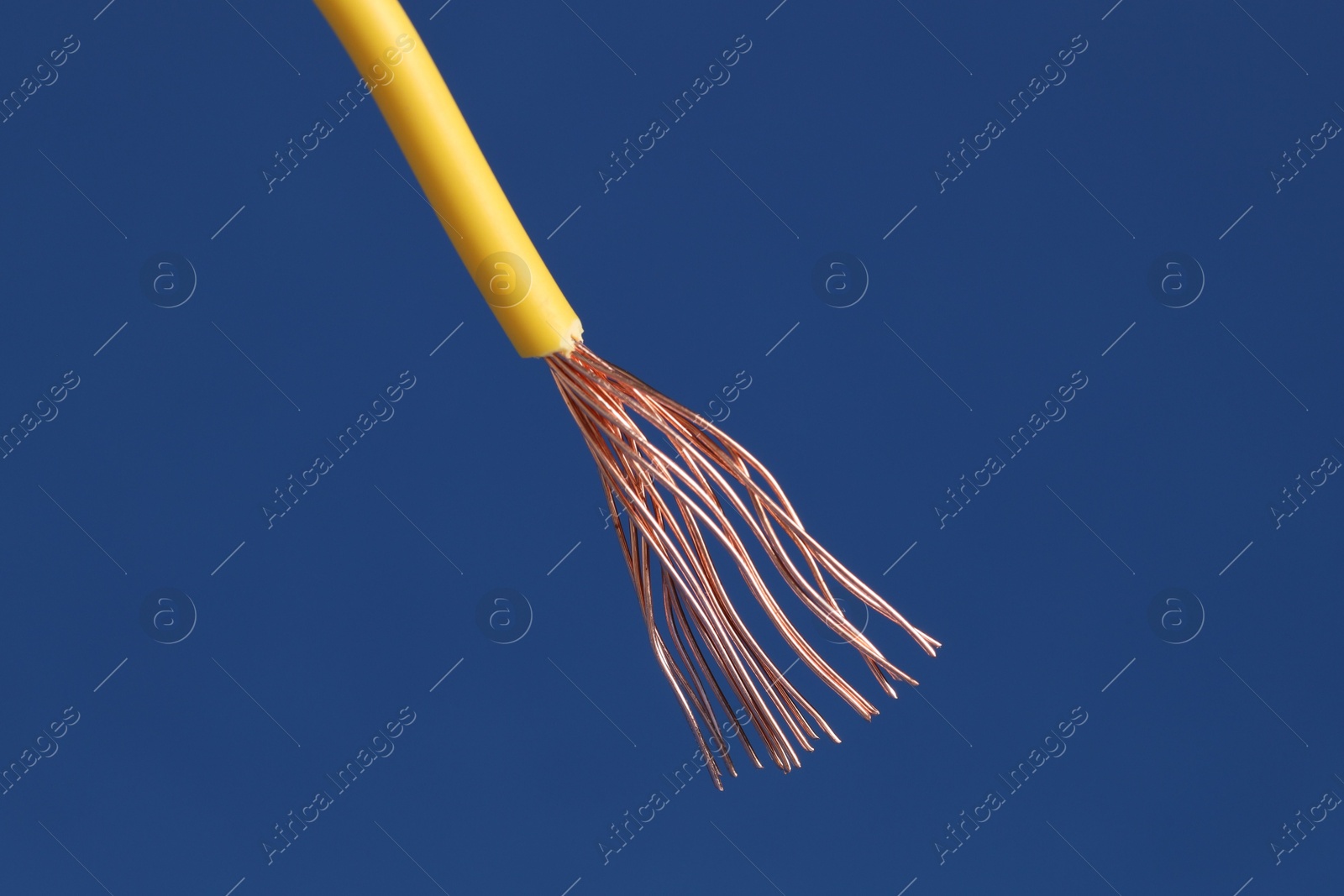 Photo of Yellow stripped electrical wire on blue background, closeup