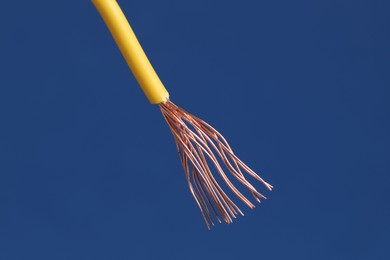 Photo of Yellow stripped electrical wire on blue background, closeup