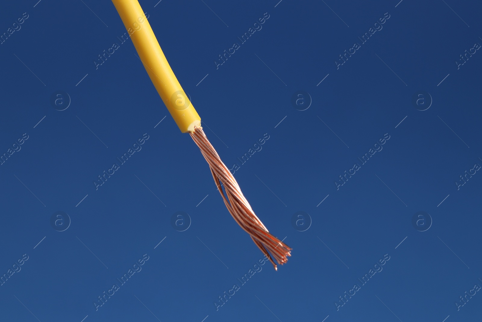 Photo of Yellow stripped electrical wire on blue background, closeup