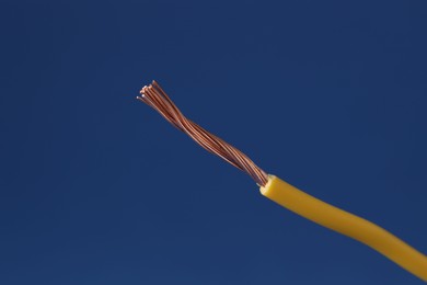 Photo of Yellow stripped electrical wire on blue background, closeup. Space for text