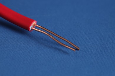 Photo of Red stripped electrical wire on blue background, closeup