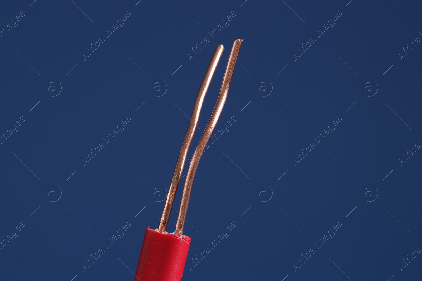 Photo of Red stripped electrical wire on blue background, closeup