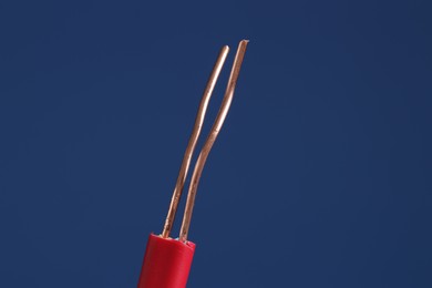 Photo of Red stripped electrical wire on blue background, closeup