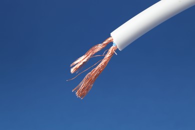 Photo of White stripped electrical wire on blue background, closeup