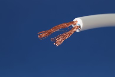 Photo of White stripped electrical wire on blue background, closeup