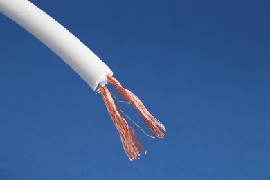 Photo of White stripped electrical wire on blue background, closeup. Space for text