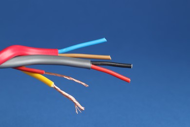 Photo of Many stripped electrical wires on blue background, closeup