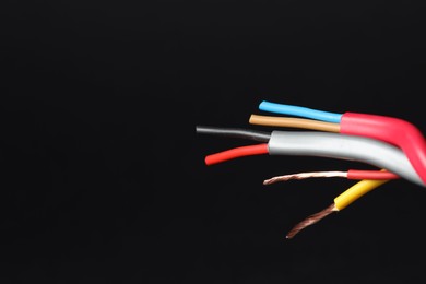 Photo of Many stripped electrical wires on black background, closeup. Space for text