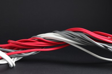 Photo of Many electrical wires on black background, closeup