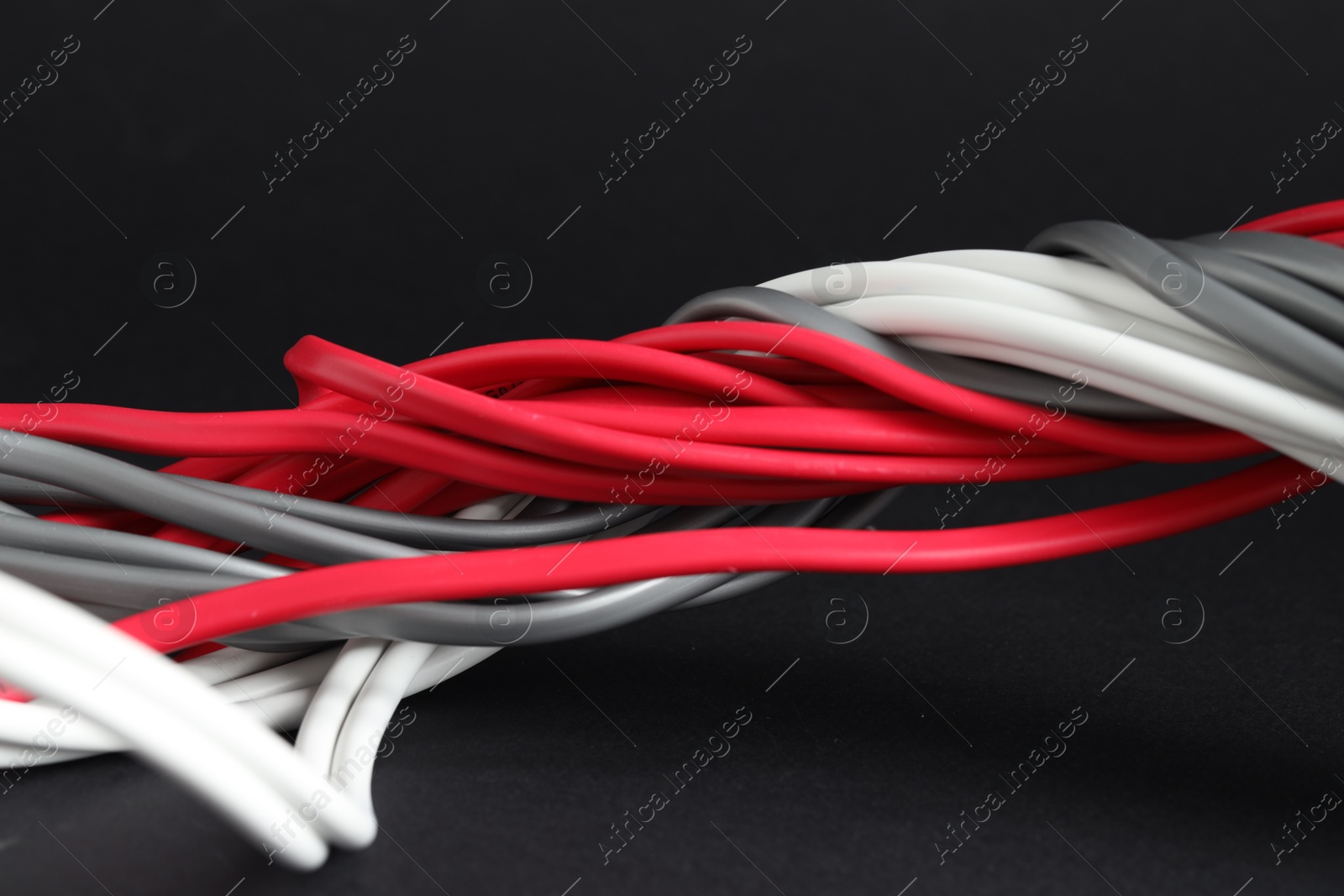 Photo of Many electrical wires on black background, closeup