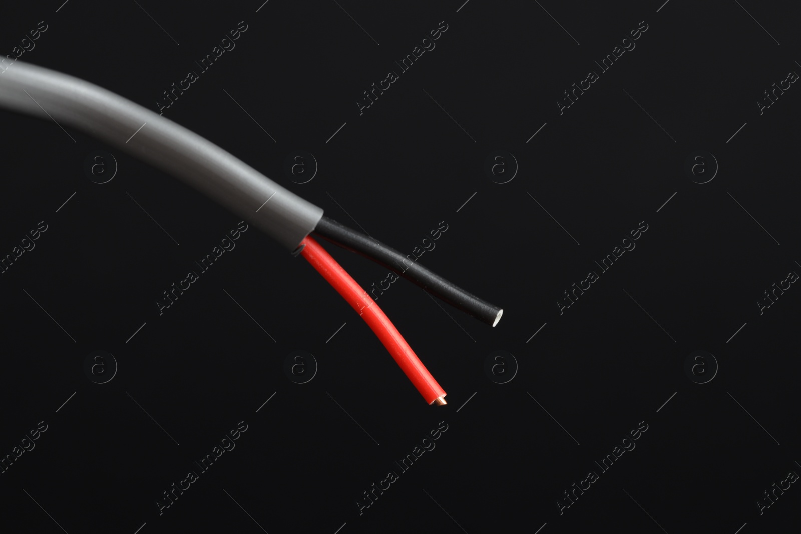 Photo of Grey stripped electrical wire on black background, closeup