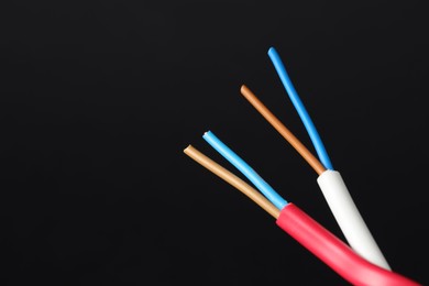 Photo of Stripped electrical wire on black background, closeup. Space for text