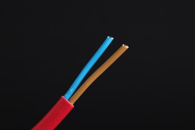 Photo of Red stripped electrical wire on black background, closeup