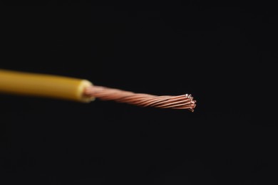 Photo of Yellow stripped electrical wire on black background, closeup. Space for text