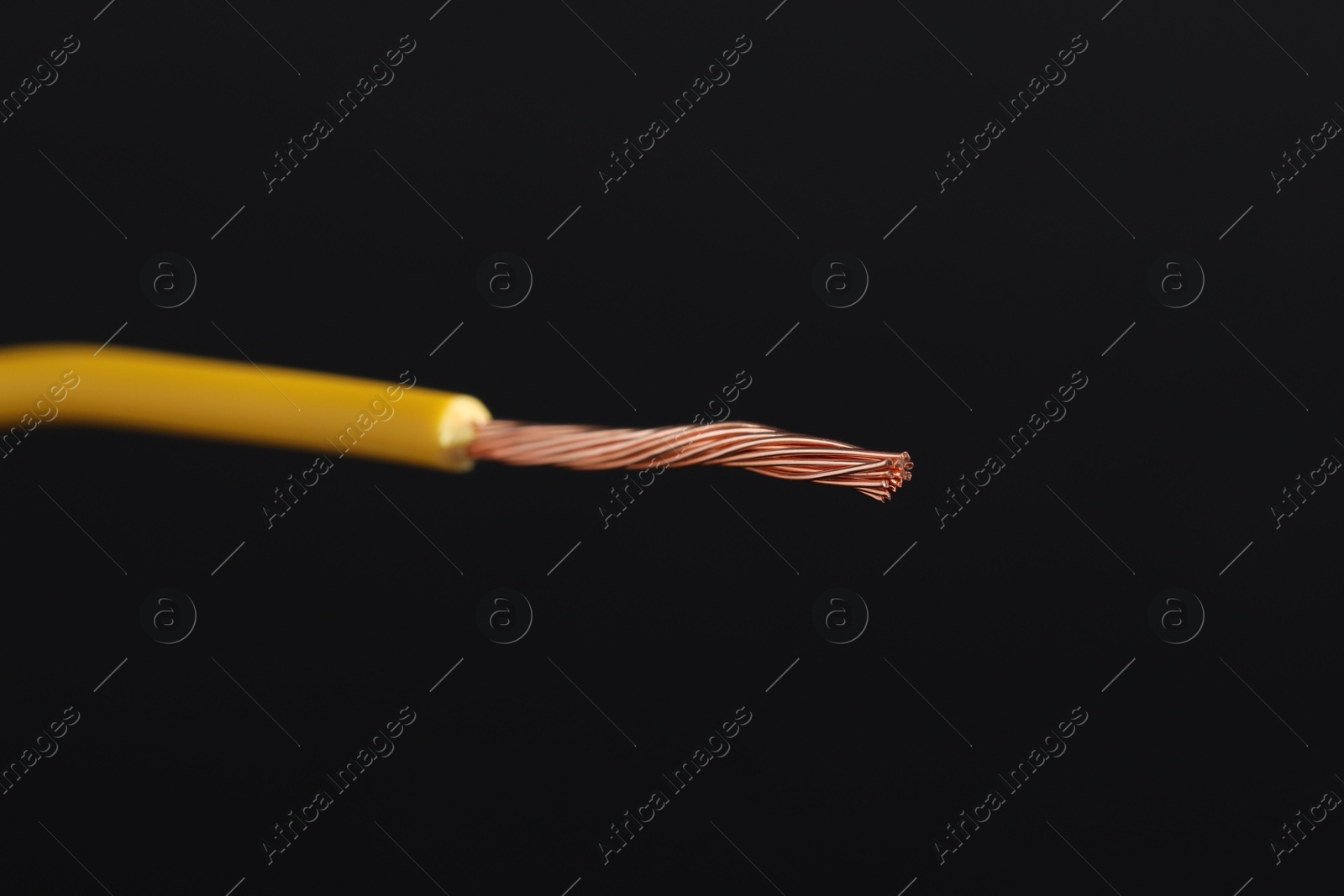 Photo of Yellow stripped electrical wire on black background, closeup. Space for text