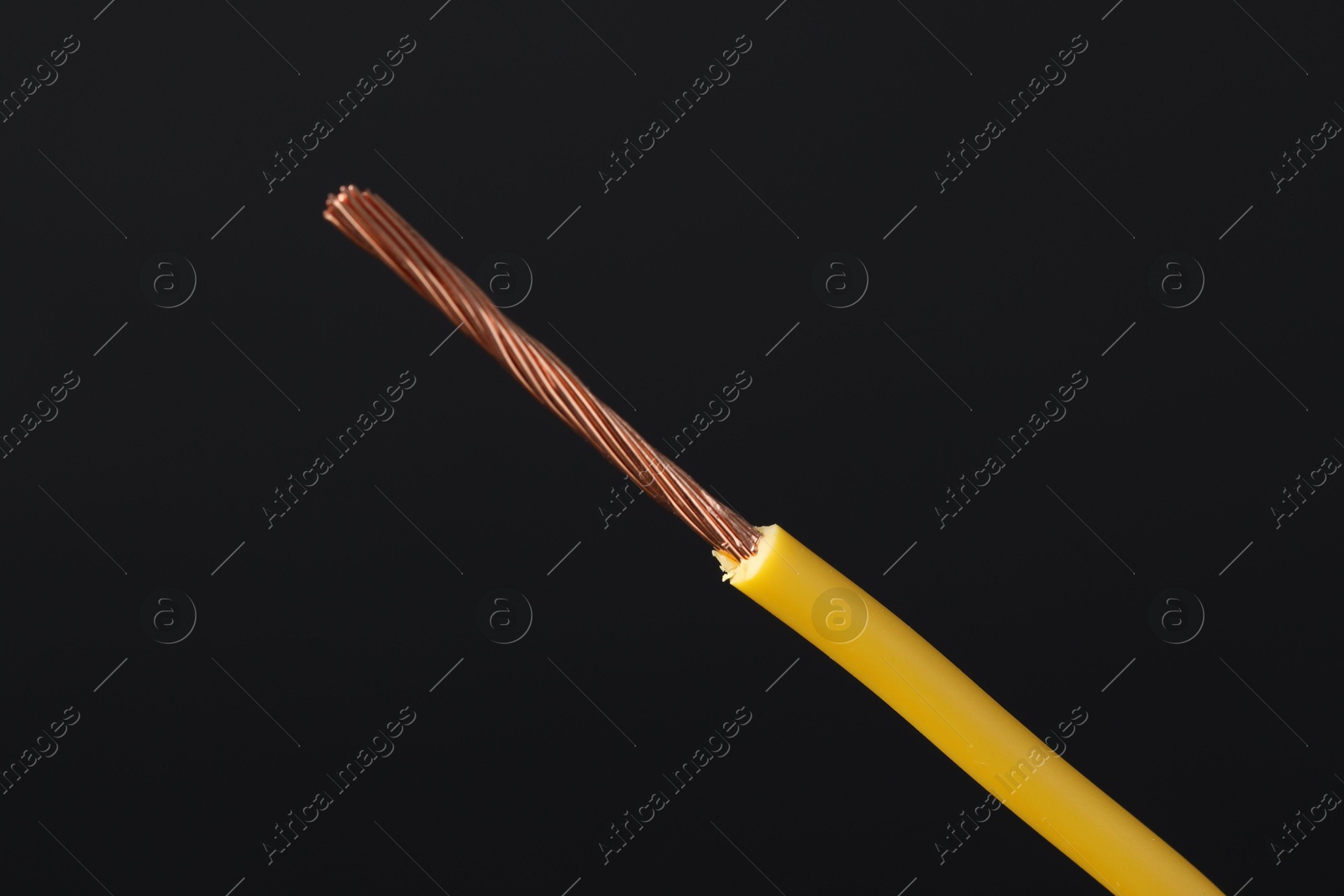 Photo of Yellow stripped electrical wire on black background, closeup. Space for text