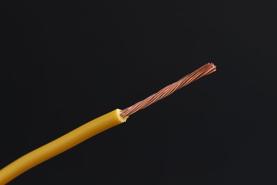 Photo of Yellow stripped electrical wire on black background, closeup. Space for text