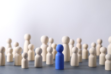 Photo of Human resources concept. Blue figure among wooden ones on table against light background, closeup. Space for text