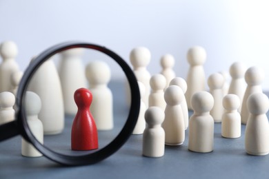 Photo of Human resources concept. Looking at wooden figures through magnifying glass on table against light background, closeup