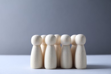 Photo of Human resources concept. Many wooden figures on table against grey background, closeup. Space for text