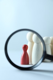 Photo of Human resources concept. Looking at wooden figures through magnifying glass on light background, closeup