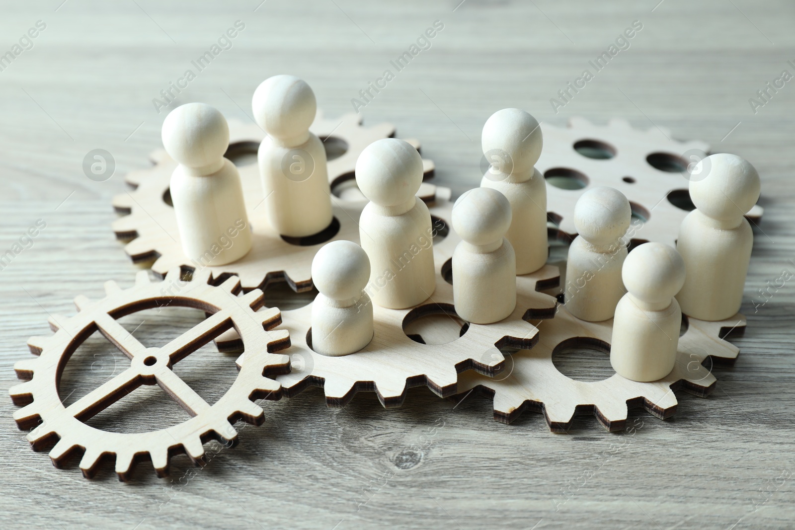 Photo of Human resources concept. Many figures and gearwheels on wooden table, closeup